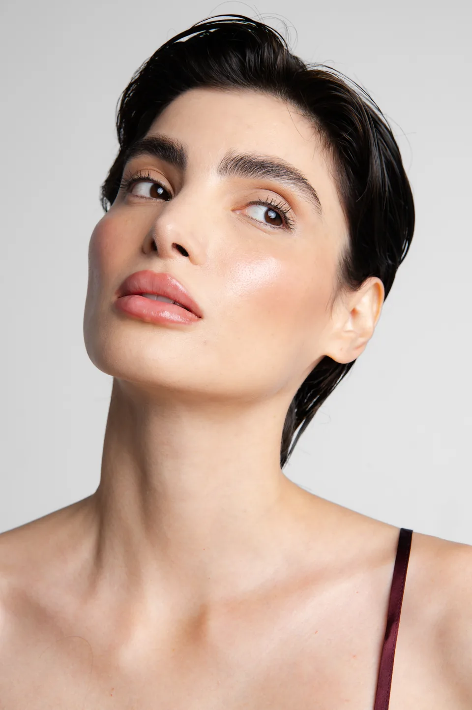 Portrait of a woman with short dark hair and glowing skin, Avora Beauty