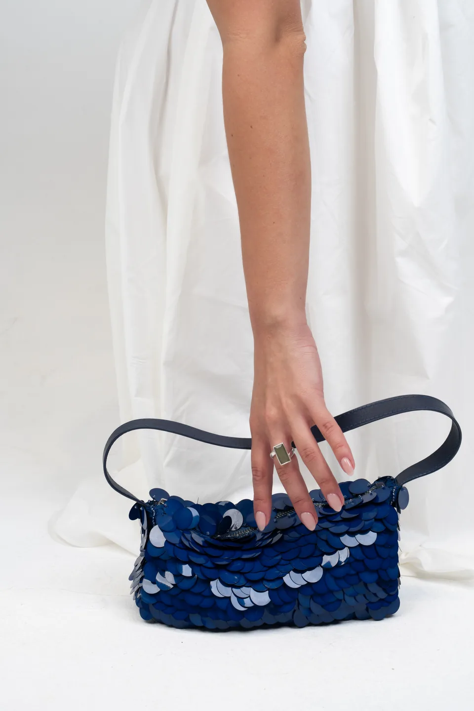 Hand holding a blue sequin handbag, e-commerce photoshoot