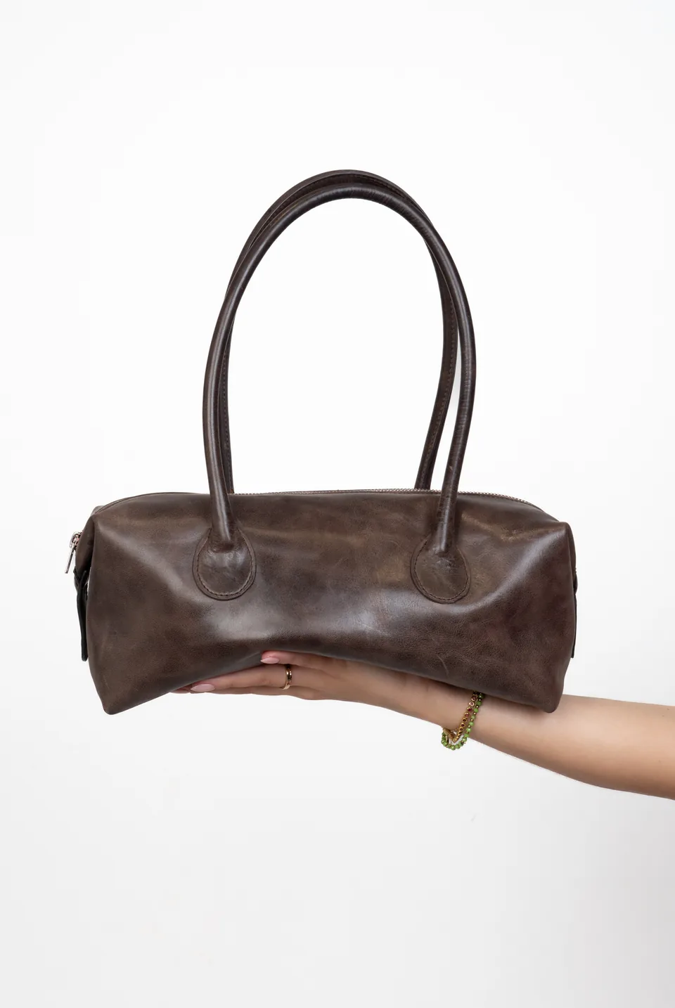 Hand holding a brown leather handbag, e-commerce photoshoot