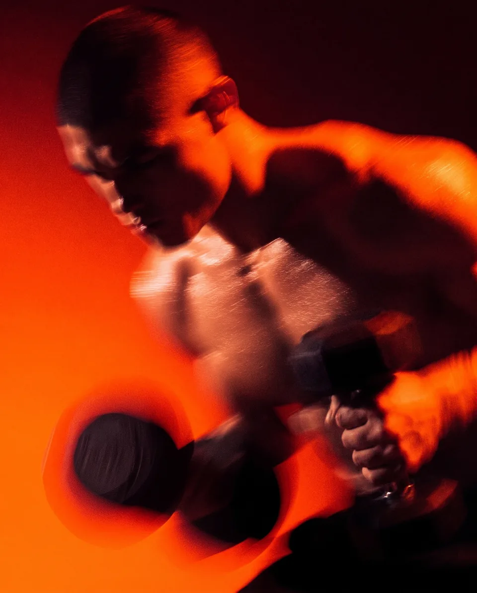 AI-generated athlete lifting a dumbbell in orange light, Chairon House