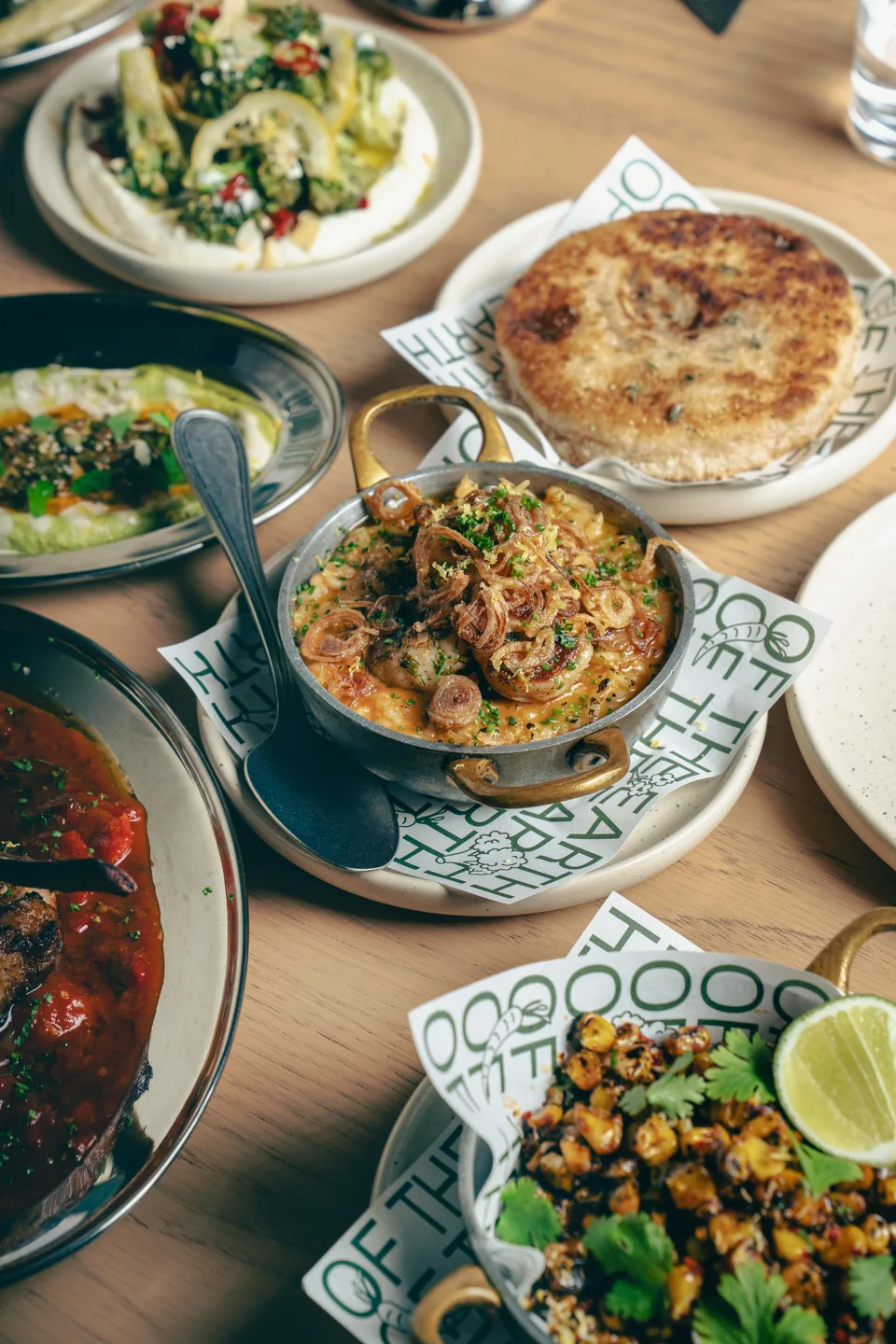 Spread of shared dishes and salads on a restaurant table, Somewhere
