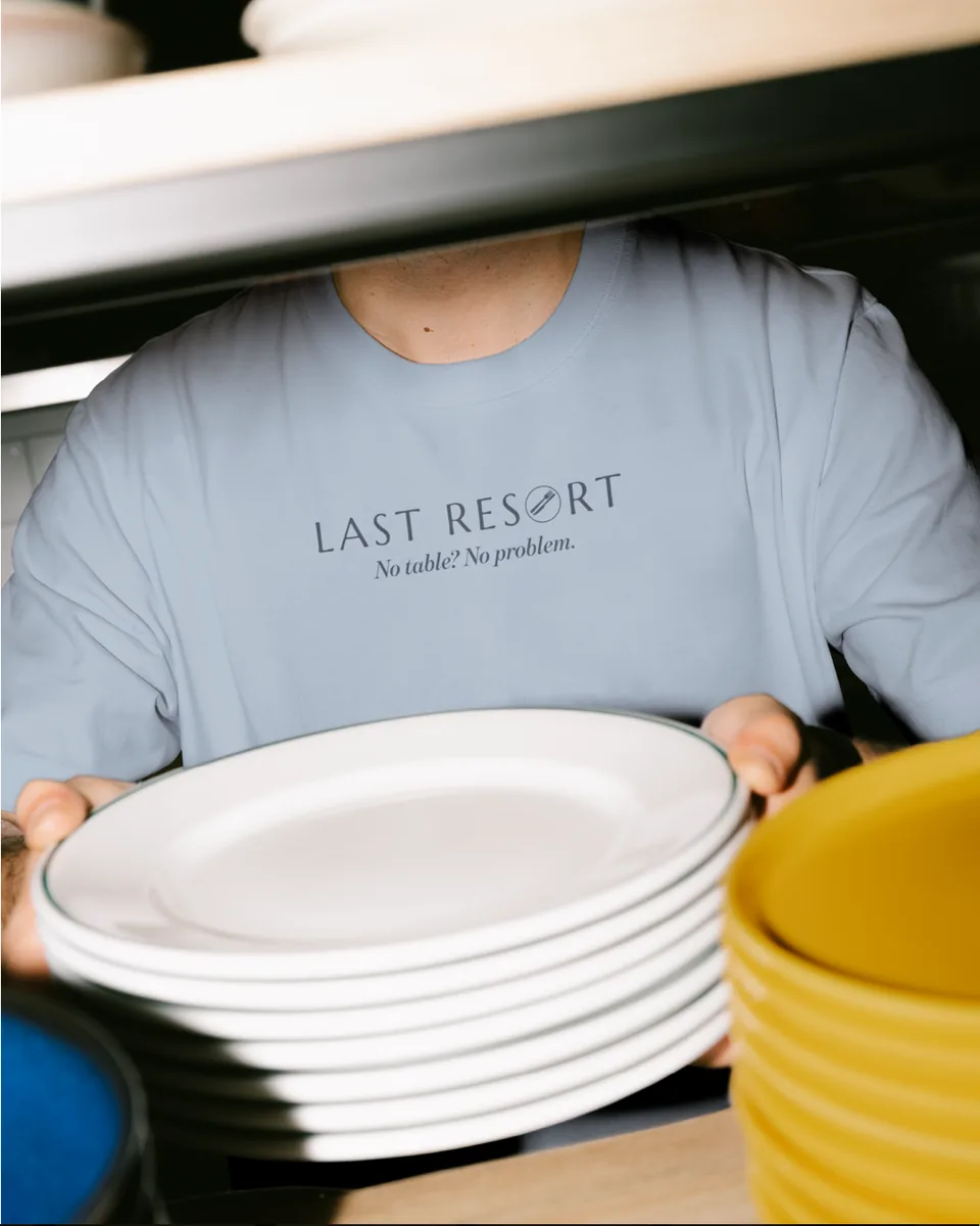 Person in a Last Resort sweatshirt carrying a stack of plates