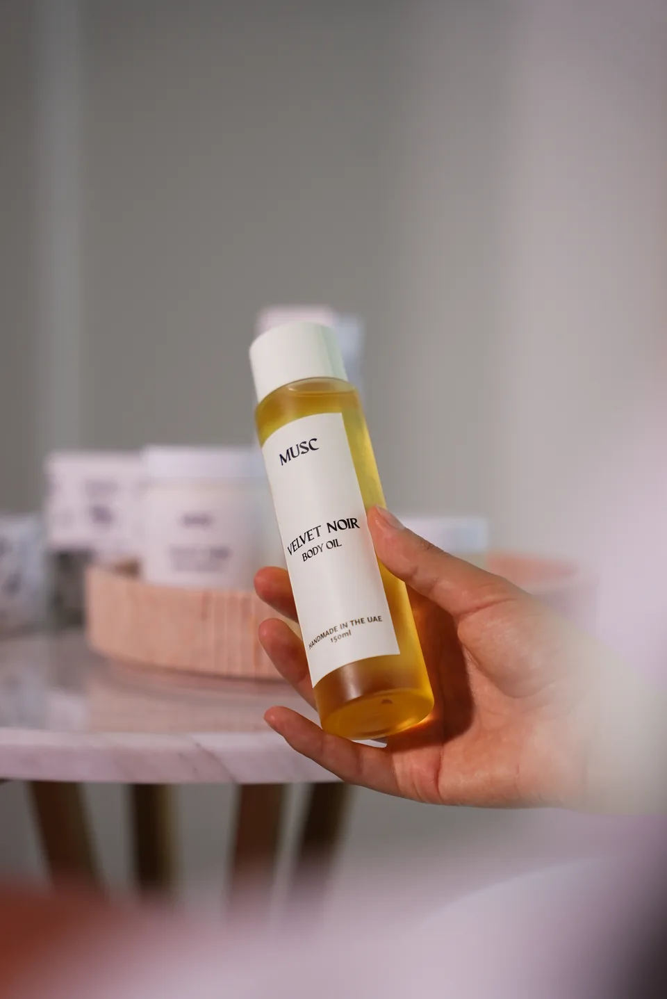 Hand holding a MUSC body oil bottle, social content