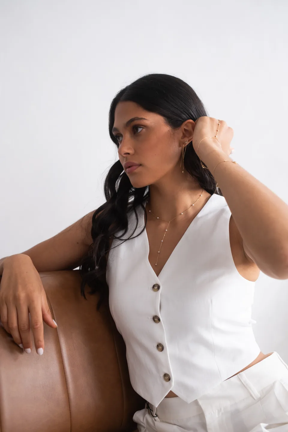 Woman in a white waistcoat seated on a leather sofa, creative direction shoot