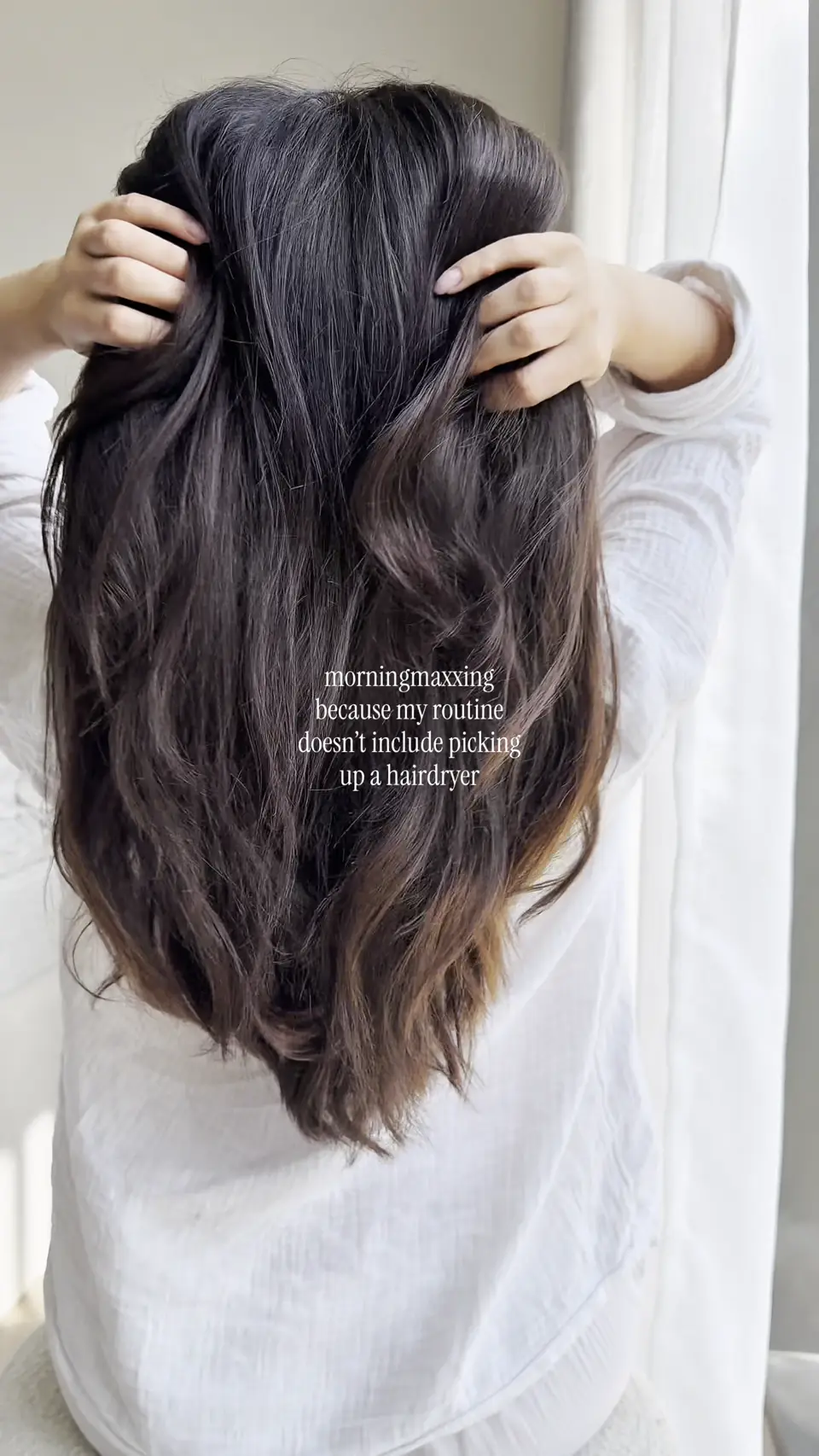 Woman styling her hair with an Avora Beauty hairdryer, from an influencer video
